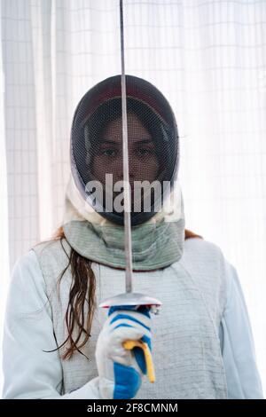 Ritratto di una giovane fencer ragazza con la maschera e. laminare al centro della faccia Foto Stock