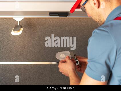 Sostituzione di Old RV Camper Lighting alle moderne luci a LED eseguite da un tecnico professionista di RV caucasico nei suoi 40 anni. Foto Stock