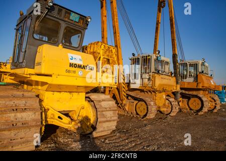 Macchine per palafitte di costruzione gialle in parcheggio. Turkestan, Kazakistan. Foto Stock