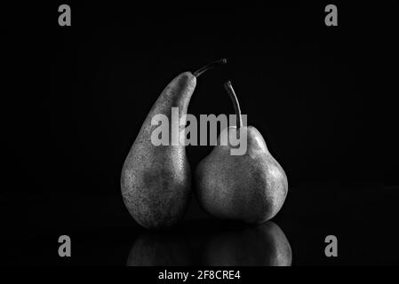 Due pere di diverse varietà su fondo nero opaco. Il concetto di tolleranza e positività del corpo. Foto Stock