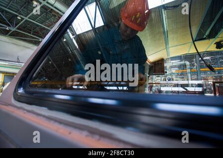Kazakistan, Nur-sultan. Impianto di costruzione locomotiva. Riflesso del lavoratore nella finestra della cabina. Foto Stock