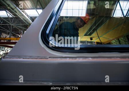 Kazakistan, Nur-sultan. Impianto di costruzione locomotiva. Riflesso del lavoratore nella finestra della cabina Foto Stock