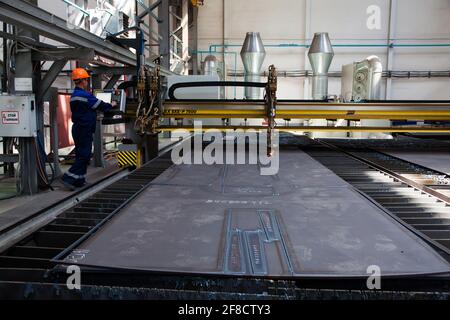 Impianto di costruzione locomotiva. Laser CNC macchina taglio parti metalliche.lavoratore in arancione hardhat sinistra. Foto Stock