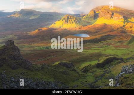 Vivace luce dorata sull'epico paesaggio montano del terreno aspro e contornato di Cleat e Dun Dubh al Quiraing sull'Isola di Skye, Scot Foto Stock