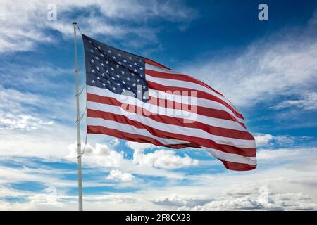 Bandiera degli Stati Uniti d'America su un palo che oscilla su sfondo blu cielo nuvoloso. Simbolo del simbolo USA. Foto Stock