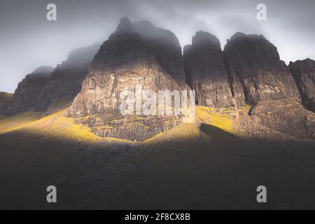 La luce e l'ombra drammatiche con foschia creano un paesaggio atomferico a forma di moodia scura presso la Storr sull'isola di Skye, nelle Highlands scozzesi. Foto Stock