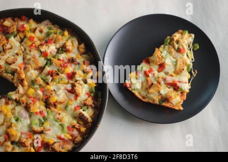 Una pizza fatta in casa a base di crosta sottile con formaggio, pollo e verdure. Scatto su sfondo bianco. Foto Stock