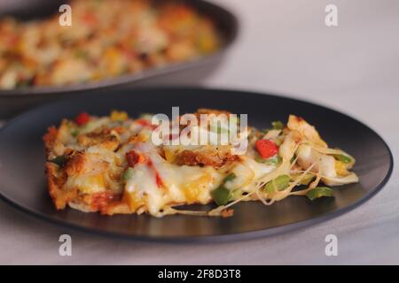 Una pizza fatta in casa a base di crosta sottile con formaggio, pollo e verdure. Scatto su sfondo bianco. Foto Stock