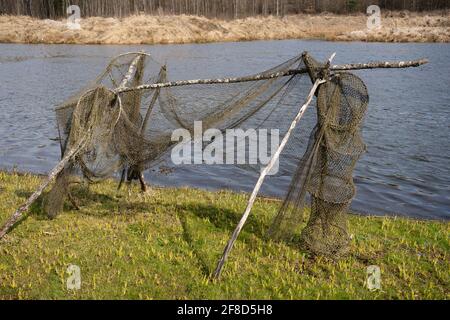 Antiche reti da pesca sono asciugate sulla riva del lago su supporti in legno Foto Stock