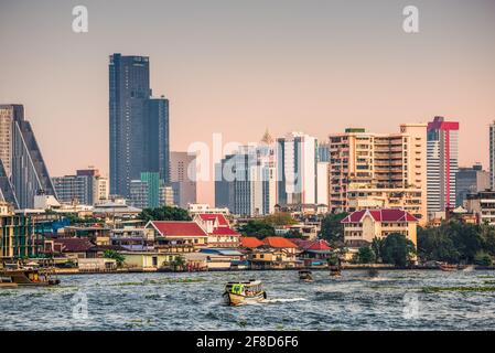 Skyline della città visto dalla barca turistica sul fiume Chao Phraya al tramonto a Bangkok, Thailandia Foto Stock