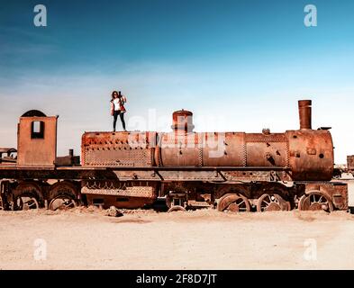 Ragazza sul treno a vapore arrugginito vicino a Uyuni in Bolivia. Treni Cimitero. Foto Stock
