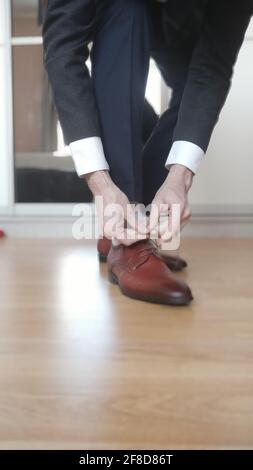 Uomo d'affari blurred che lega le scarpe sulle sue scarpe marroni Foto Stock