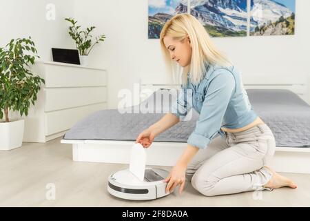 Primo piano di donna attiva l'aspirapolvere robot intelligente Foto Stock