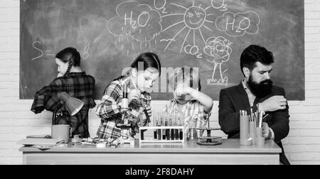 Affascinante lezione di chimica. L'uomo ha sopportato l'insegnante e gli allievi con i tubi di prova in classe. Laboratorio chimico scolastico. La scienza coinvolge la teoria. Scuola Foto Stock