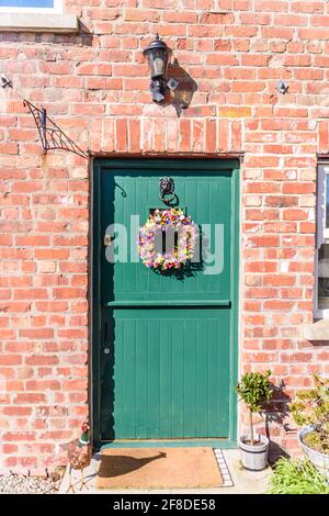 Corona floreale su un ingresso stabile porta ad un cottage fienile irlandese piuttosto convertito. Foto Stock