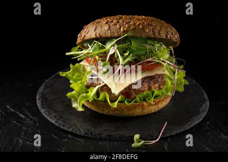 sandwich chiuso in un panino con cetriolo, pomodoro e micrograni. Hamburger fatto in casa Foto Stock