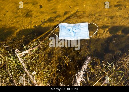 Uno usato maschera pazzesca galleggiante in un piccolo fiume, primo piano. Foto Stock