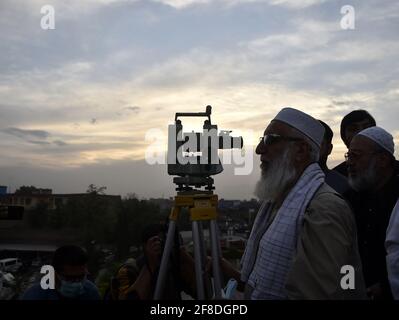 Peshawar. 13 Apr 2021. Un uomo osserva la luna crescente attraverso un telescopio nel Peshawar del Pakistan nord-occidentale il 13 aprile 2021. La luna a mezzaluna del Ramadan è stata avvistata in Pakistan martedì sera e il mese santo inizierà ufficialmente mercoledì, secondo un annuncio ufficiale del comitato di avvistamento della luna del paese. Credit: Saeed Ahmad/Xinhua/Alamy Live News Foto Stock