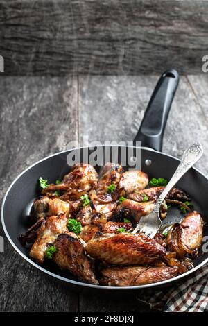 Ali di pollo arrosto in padella su tavolo di legno Foto Stock