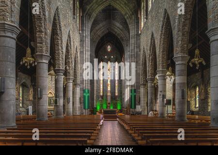 Killarney, Irlanda, agosto 2019 interni, file di panche, colonne alte, Vetrate e altare maggiore nella Cattedrale di San Marys Foto Stock