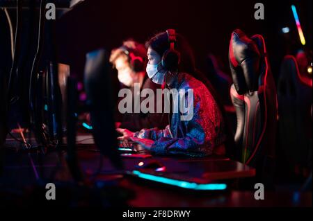 Un team multirazziale di cybersportsmen in maschere mediche si esibisce a. un prestigioso torneo di cyber-giochi durante la pandemia del coronavirus Foto Stock