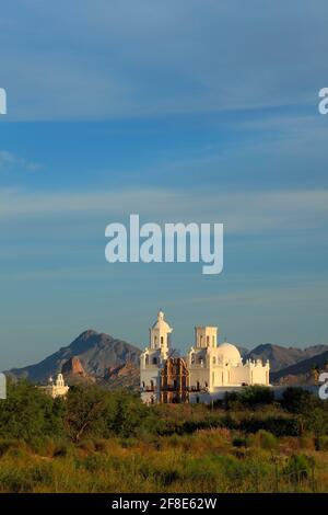 Riserva indiana di Tohono o'odham AZ / Oct luce del mattino presto Scalda la missione Kino di San Xavier retroped da Red Butte e Cat Mountain sotto a. Foto Stock