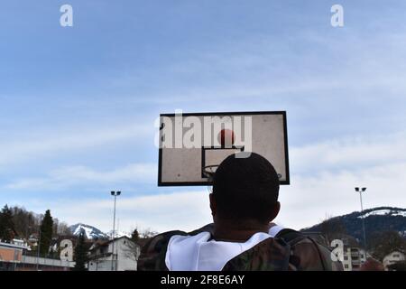 Vista posteriore di un giocatore di basket che guarda la palla cadendo nella rete Foto Stock