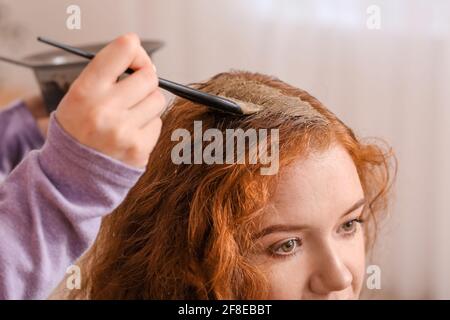 Tingere i capelli della giovane donna con l'hennè in salone di bellezza Foto Stock