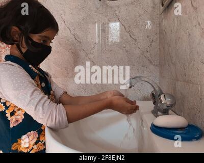 Bambini mascherati lavarsi le mani durante il coronavirus blocco in india. Foto Stock