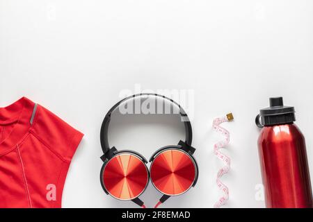 Nastro di misurazione, bottiglia d'acqua, cuffie e abbigliamento sportivo su sfondo bianco. Concetto di fitness, sport e allenamento piatto con spazio per la copia. Foto Stock