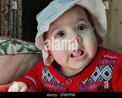 Bella ragazzina pose diverse sembra molto bello. I bambini piccoli dopo il loro nascita hanno guance morbide e un volto innocente con un sorriso sguazzante. Foto Stock