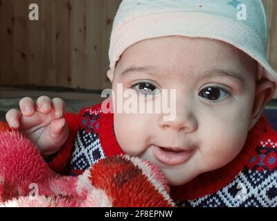 Bella ragazzina pose diverse sembra molto bello. I bambini piccoli dopo il loro nascita hanno guance morbide e un volto innocente con un sorriso sguazzante. Foto Stock