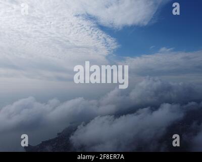 Alto sopra la fitta nebbia, come un bellissimo oceano di nuvole all'alba. Il sole sorge sopra il mare infinito di nuvole fino all'orizzonte. Natura incredibile Foto Stock