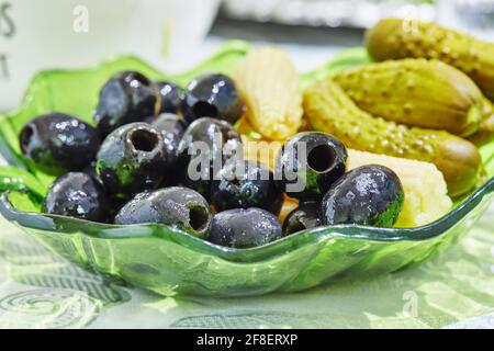 Olive, sottaceti e mais, in un piatto sul tavolo Foto Stock