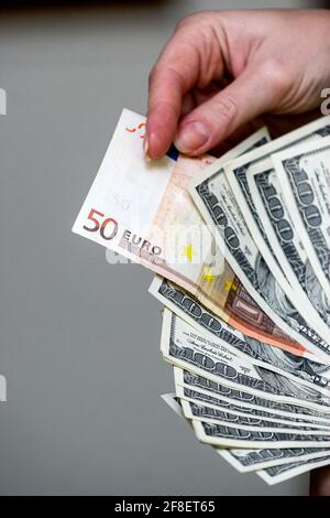 Minsk. Bielorussia - 17.04.2009: Bollette da cento dollari e banconote da 50 euro in una mano su sfondo grigio. Foto Stock