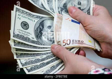 Minsk. Bielorussia - 17.04.2009: Bollette da cento dollari e banconote da 50 euro in una mano su sfondo grigio. Foto Stock