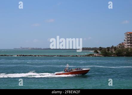 La barca viaggia veloce nell'acqua dell'oceano con la gente a bordo che entra nel porto marittimo di Miami presso la spiaggia di South Pointe a Miami Beach, Florida, ha visi offuscati Foto Stock