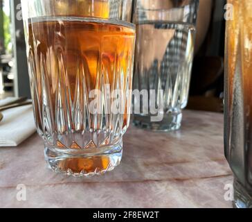 Dettagli di una tazza di vetro con tè freddo all'interno gustati in una calda giornata estiva. Foto Stock