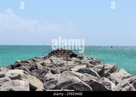 Blu oceano panorama della costa sud della spiaggia, florida del sud, riflesso del sole e onde calme, mucchio di rocce nel mare, percorso roccioso. CopySpace, sfondo Foto Stock