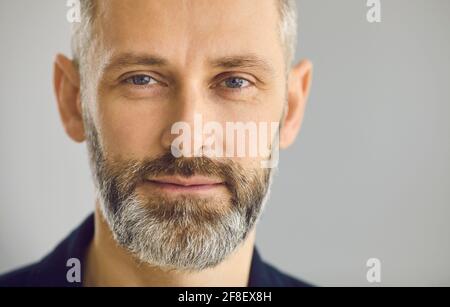 Primo piano ritratto di felice uomo d'affari maturo sopportato sopra sfondo grigio studio Foto Stock