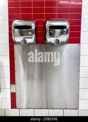 Un moderno asciugatore è appeso a una parete in un bagno pubblico. Igiene. Pulizia delle mani. Lavarsi le mani. Stare al sicuro dalla pandemia di Covid-19 Foto Stock