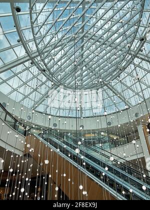 Luci a dangling all'interno del centro commerciale Aventra, nella Florida meridionale. Decorazioni interne per il pubblico. Graziose luci appese vicino alla scala mobile. Foto Stock