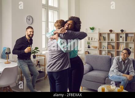 Due giovani eccitati si abbracciano mentre si incontrano a una festa di riunione degli amici Foto Stock
