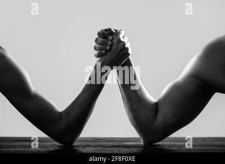 Armi che lottano con la mano sottile e un grande braccio forte in studio. Braccio wrestling. Braccio uomo molto muscled che lotta un uomo debole puny. Due mani dell'uomo si sono aggrappate al braccio Foto Stock