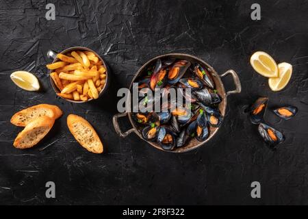 Cozze, colpo d'asta con patatine fritte, limone e pane tostato Foto Stock