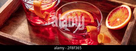 Cocktail Negroni con panorama delle arance sanguigne su sfondo rustico Foto Stock