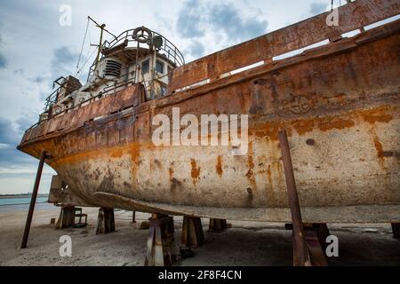 Mangystau, Kazakhstan - 19 maggio 2012: Vecchia nave arrugginita sul Mar Caspio, baia di Bautino, cantiere di riparazione navale. Cielo nuvoloso grigio. Foto Stock