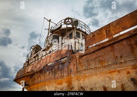 Mangystau, Kazakistan - 19 maggio 2012: Baia di Bautino. Vecchia nave in acciaio arrugginito sul cantiere di riparazione navale del Mar Caspio. Grigio nuvoloso tempesta cielo sfondo. Primo piano Foto Stock