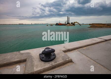 Mangystau, Kazakhstan: Terminal di carico della nave sul cantiere navale del Mar Caspio. Bullard in metallo nero. Lavora per l'isola artificiale. Nuvole grigie Foto Stock