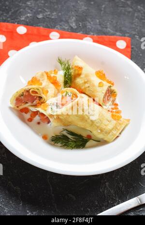 Deliziosa colazione - crepes con salmone affumicato, panna acida e caviarca su fondo di pietra nera. Foto Stock